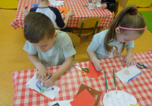Dwoje dzieci projektu swój banknot, rysują kredkami.